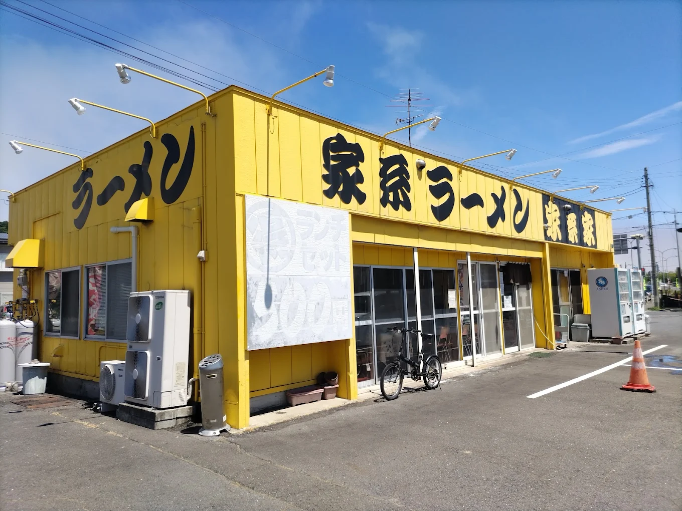 家系家八戸店の外観：黄色い建物に黒い筆文字で「家系ラーメン」